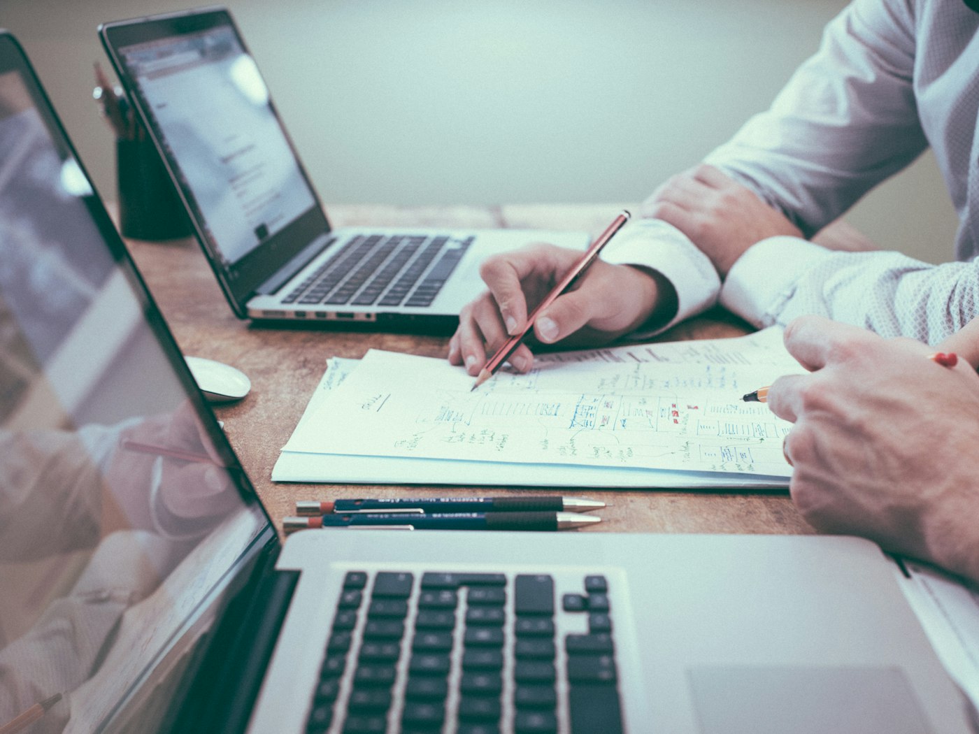 Two professionals collaborating at a desk with laptops and financial notes